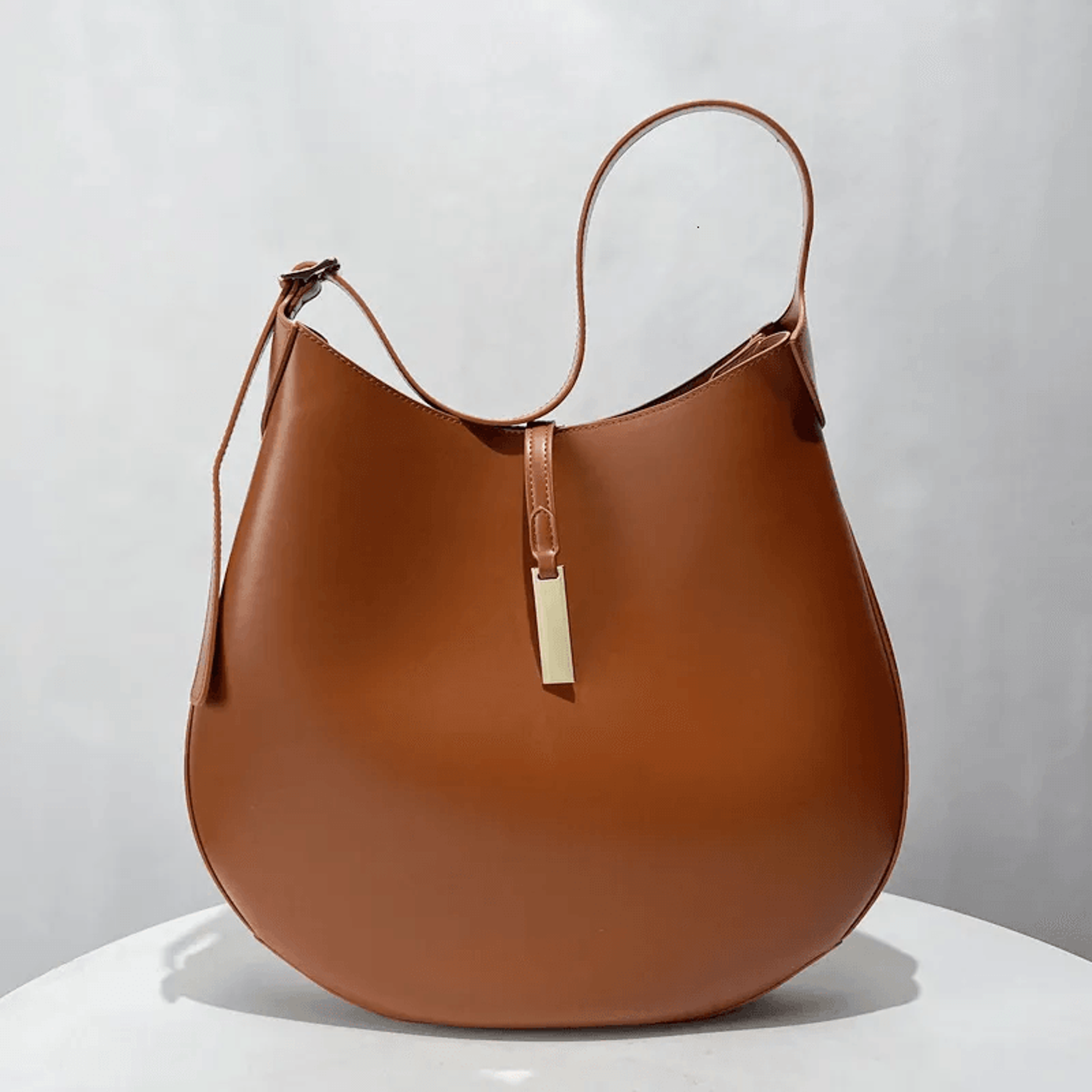 black minimalist hobo bag with gold bar accent and adjustable strap