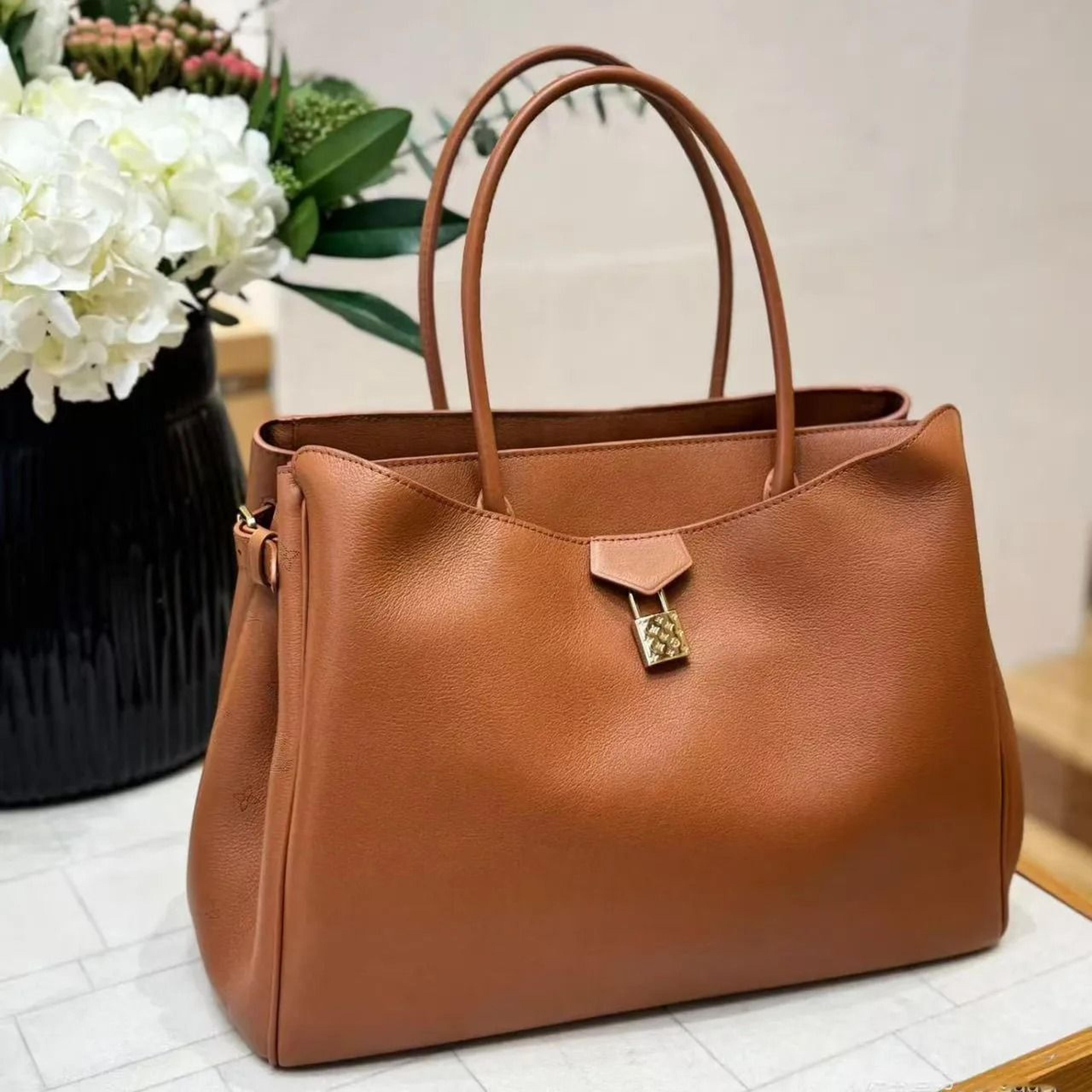 large leather tote bag with metal lock closure and shoulder crossbody design