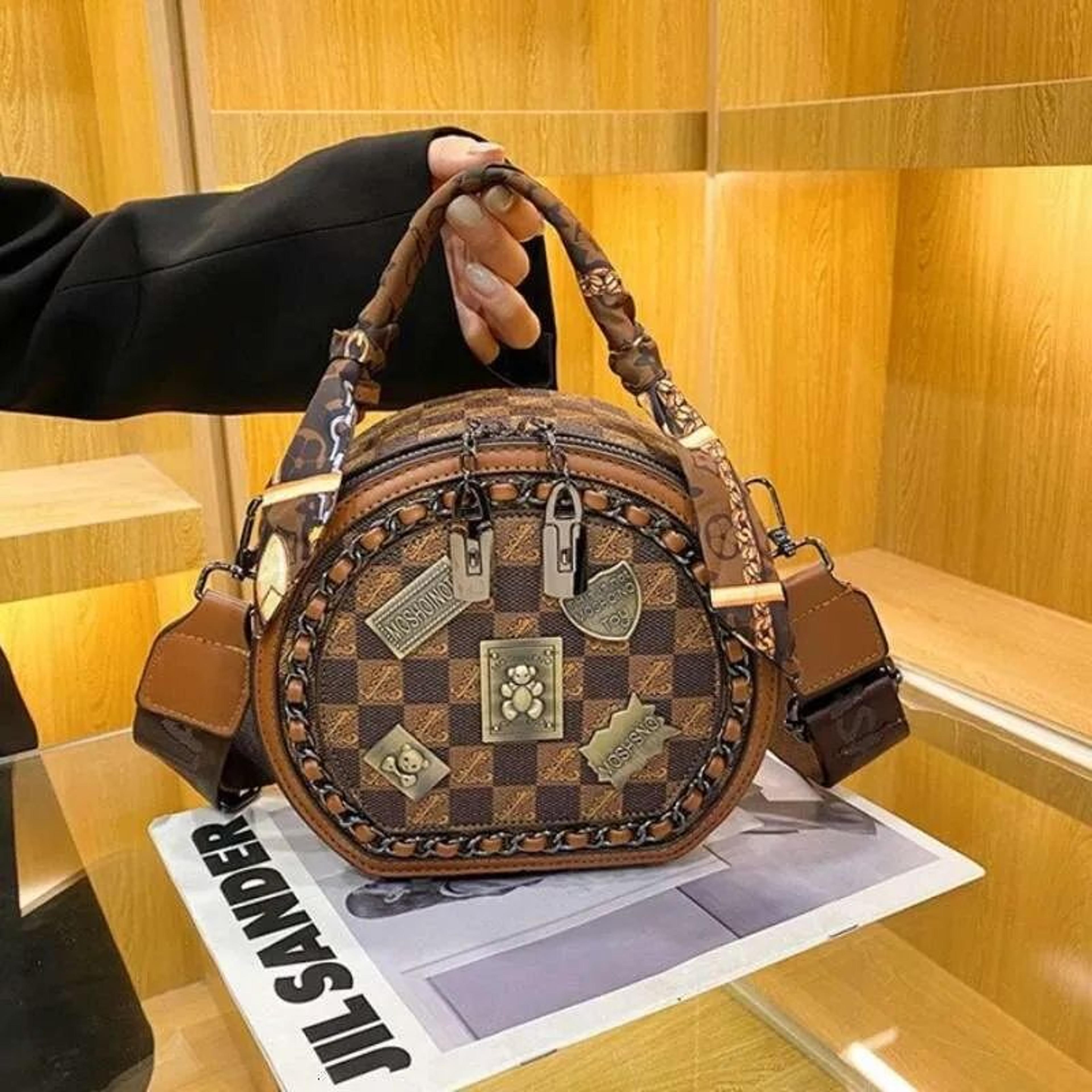 women small round crossbody bag with adjustable wide strap and badge detail
