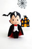 Felt vampire Count Dracula standing in the background of painted Halloween decorations