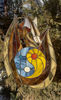 Stained glass window panel of a dragon with sun and moon yin yang in the middle is hanging in front of a Thuja tree.jpg