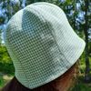 A bell hat made of linen fabric with a houndstooth print. Panama hat with a pied-de-poule print. Mint panama hat  tulip.