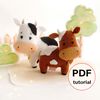 Felt farm animals - cute cows stand in the background of painted tree and fence
