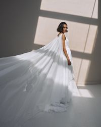 Cascading skirt wedding dress. Veil tulle bridal gown. V neckline light dress with cape.