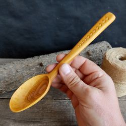 Handmade wooden spoon from natural apricot wood with decorated handle for serving or cooking