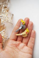 A pair of tiny needle felted cockatiels