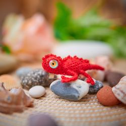 A small red crocheted brooch lizard for a jacket or backpack.