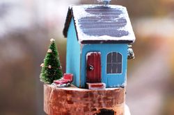 Festive winter house miniature. Sky blue cottage with a christmas tree and retro sled.