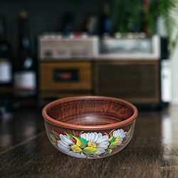 Pottery is a deep bowl. Handmade red clay. A bowl with a colored pattern