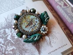 Order brooch, pendant in vintage style, with voluminous embroidery of leaves, with the image of a bird on a twig,