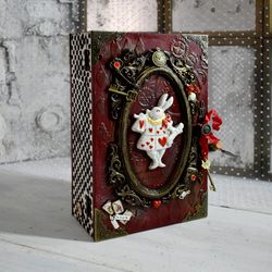 a red book-box with a white rabbit from alice in wonderland