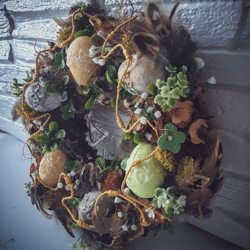 Spring Easter wreath made of willow vines, feathers, foam eggs, artificial flowers and branches.Table decoration .