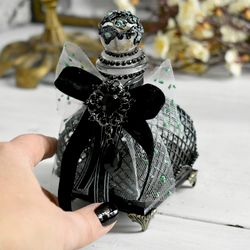 black glass bottle for storing perfumes and aroma oils with a voluminous decor