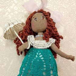 crocheted doll in a turquoise dress with an umbrella