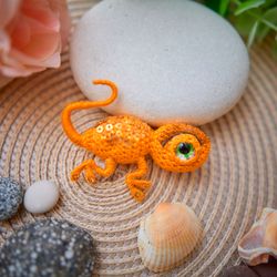 A small yellow crocheted brooch lizard for a jacket or backpack.