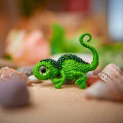 A small green crocheted brooch lizard for a jacket or backpack.