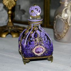 Lilac glass bottle for storing perfumes and aroma oils with a voluminous decor
