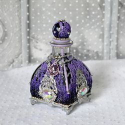lilac glass bottle for storing perfumes and aroma oils with a voluminous decor