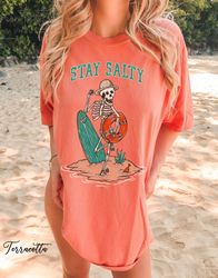 Stay Salty in T-Shirt Png: Unisex Beach Shirt Png, Summer Casual Tee with Skull Surfing Design & Ocean Theme