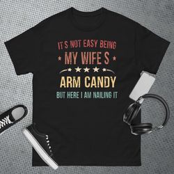 its not easy being my wifes arm candy here i am nailing it t-shirt