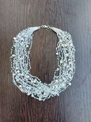 A white small delicate airy layered necklace made of beads and pearls, crocheted, a decoration for every day