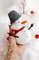 Felt snowman toy with a pail in the author's hand on the head on the background of snow