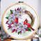 This is a cross stitch pattern with Christmas poinsettia and red cardinals in the form of a wreath.
