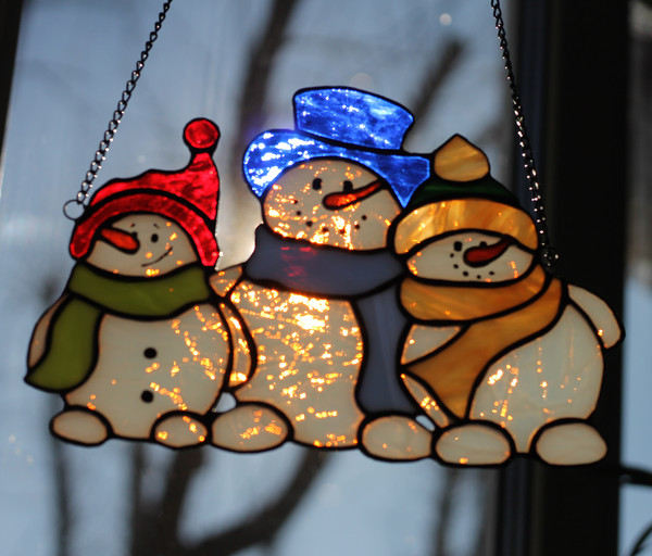 Christmas-stained-glass-suncatcher-family-of-snowmen-hanging-on-window-The-white-glass-of-which-the-snowmen's-bodies-are-made-has-an-unusual-effect-and-shines-w