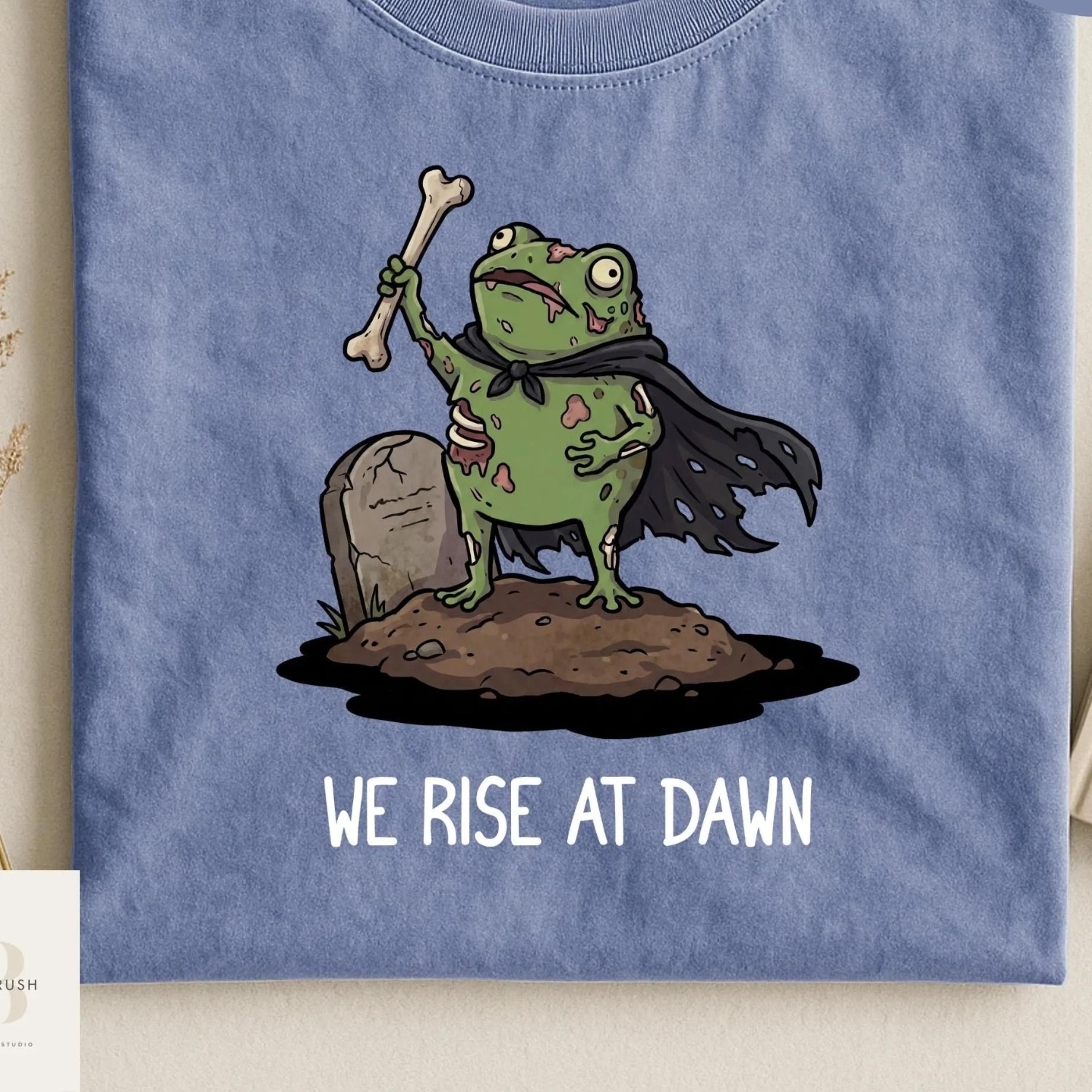 we rise at dawn halloween shirt, funny frog meme zombie tee, cute summerween tshirt, spooky season shirt