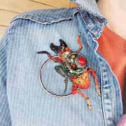 Red embroidered horned beetle with vintage elements and rings. Brooch or pendant