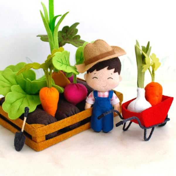 Felt farmer baby boy with a shovel, wheelbarrow and vegetable garden