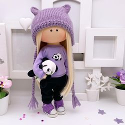 Fashionable rag textile doll in a lilac sweatshirt with PANDA print and black sweatpants. With a funny little panda