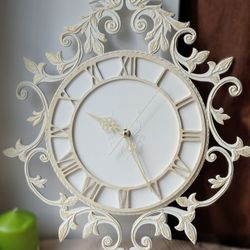 Small white wall clock with gold ornament in vintage style with Roman numerals