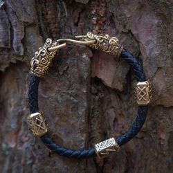 Bracelet on black leather braided cord with wolf heads and runes. Odin viking bangle. Pagan handcrafted jewelry.