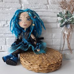 Interior textile art doll with an embroidered face and dreadlocked hair