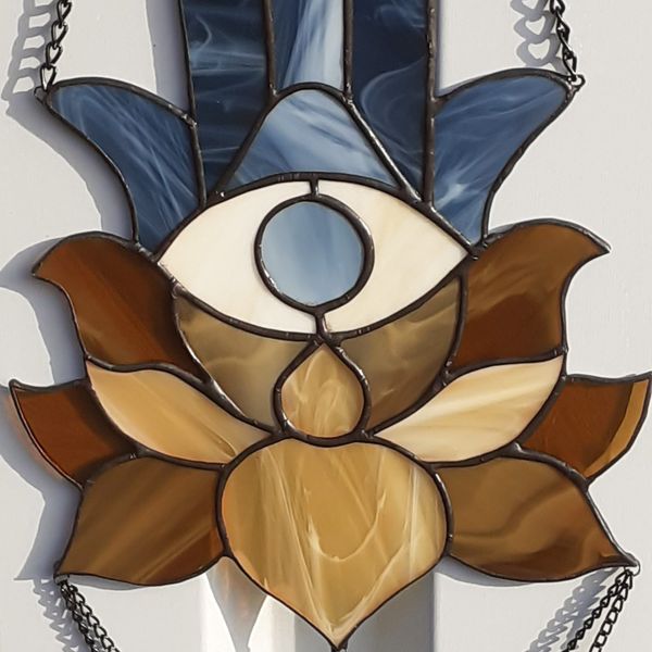 20201108-Stained glass blue Hamsa suncatcher with brown and beige lotus flower hanging in front of a white metal fence.jpg