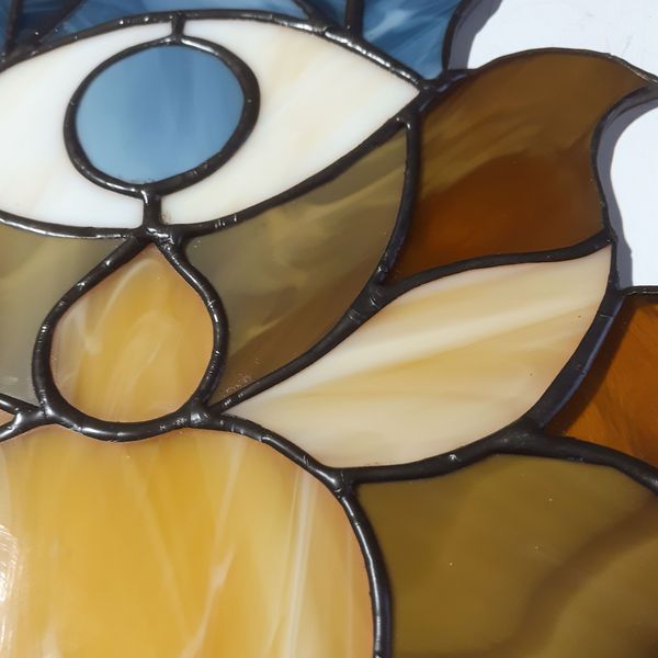 20201108-Stained glass depicting brown and beige lotus flower and white eye with blue pupil on top of the lotus black patina covered.jpg