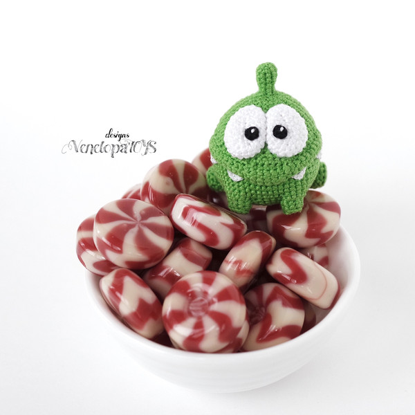 Amigurumi Om Nom from the cartoon Cut the Rope on a plate of candy