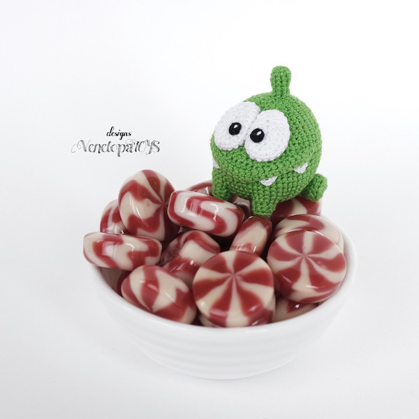 Amigurumi Om Nom from the cartoon Cut the Rope on a pile of candy