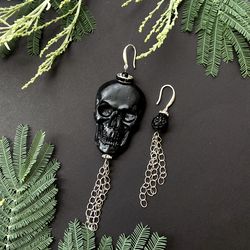 asymmetrical hanging black skull earrings with a chain
