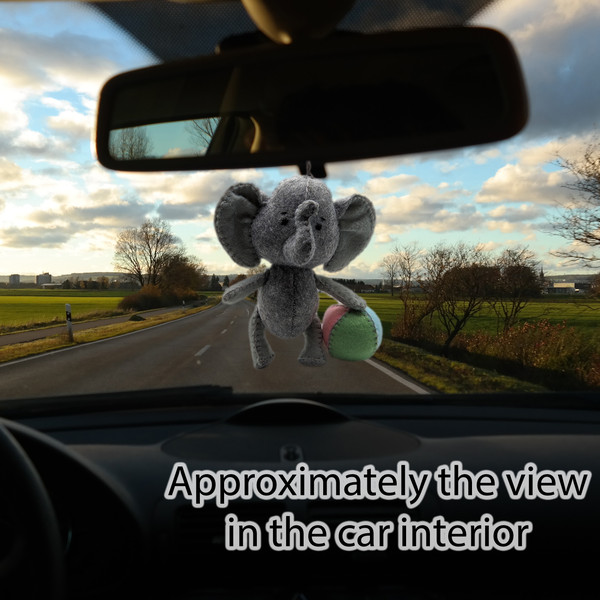 The elephant is hanging on the rearview mirror in the car.jpg