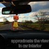 A stitched red fox hangs on a string on the rearview mirror in a car.jpg