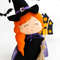 Felt Halloween toy - witch in the pointed hat with a broomstick standing in the background of painted Halloween decorations, left side view