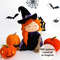 Felt Halloween toy - witch in the pointed hat with a broomstick with orange Halloween pumpkins standing in the background of painted Halloween decorations