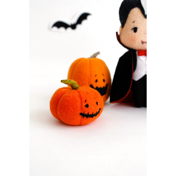 Felt orange Halloween pumpkins standing near the vampire Count Dracula in the background of painted Halloween decorations