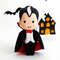 Felt vampire Count Dracula standing in the background of painted Halloween decorations