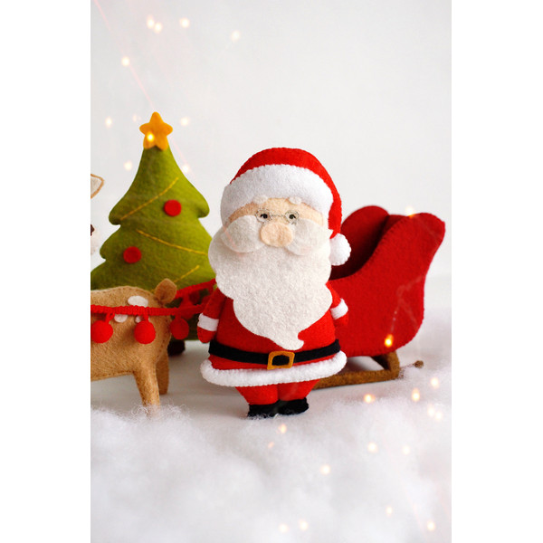 Felt Santa Claus near the Santa's sleigh, the Christmas tree and reindeer Rudolph toys