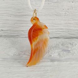 The carnelian angel wing pendant is a protective amulet for both her and him.