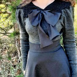gray pullover with black openwork collar and bow.