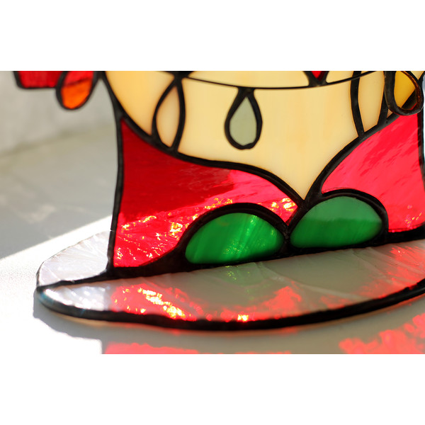 Enlarged-fragment-of-a-white-coaster-for-a-stained-glass-suncatcher-Christmas-gnome-with-garland-in-a-red-coat-and-green-boots-Colored-shadow-of-the-suncatcher-